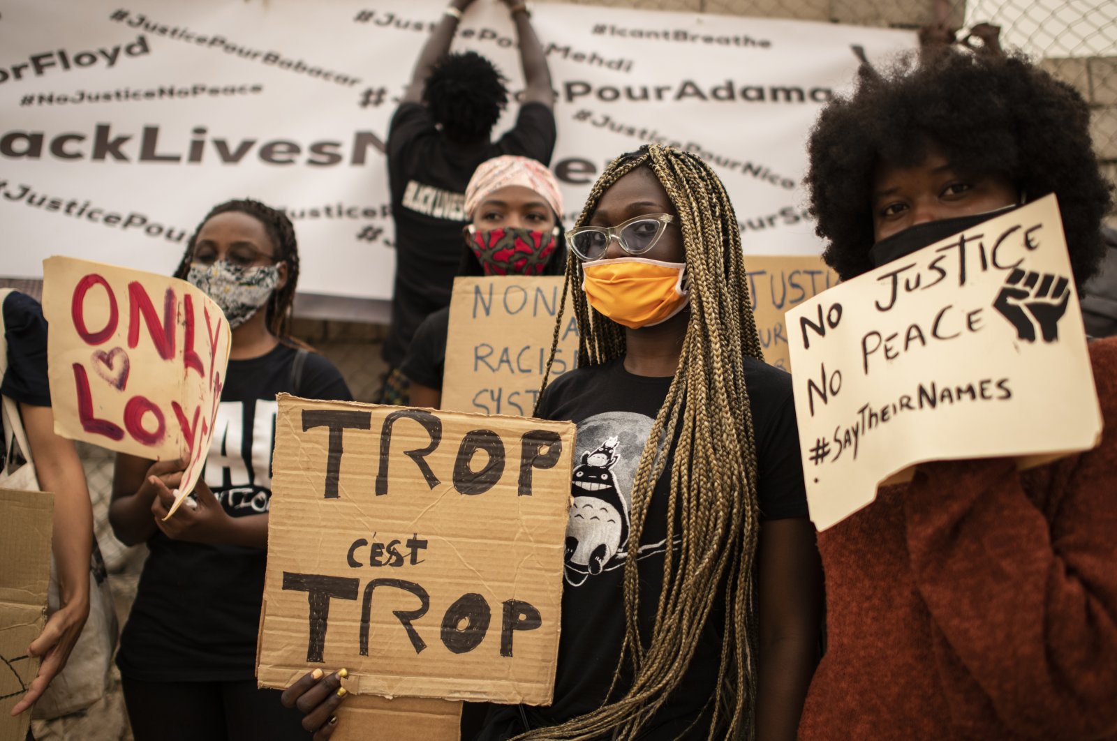 Protesters hold placards in front of the African Renaissance Monument, Dakar, June 6, 2020. (AP Photo)