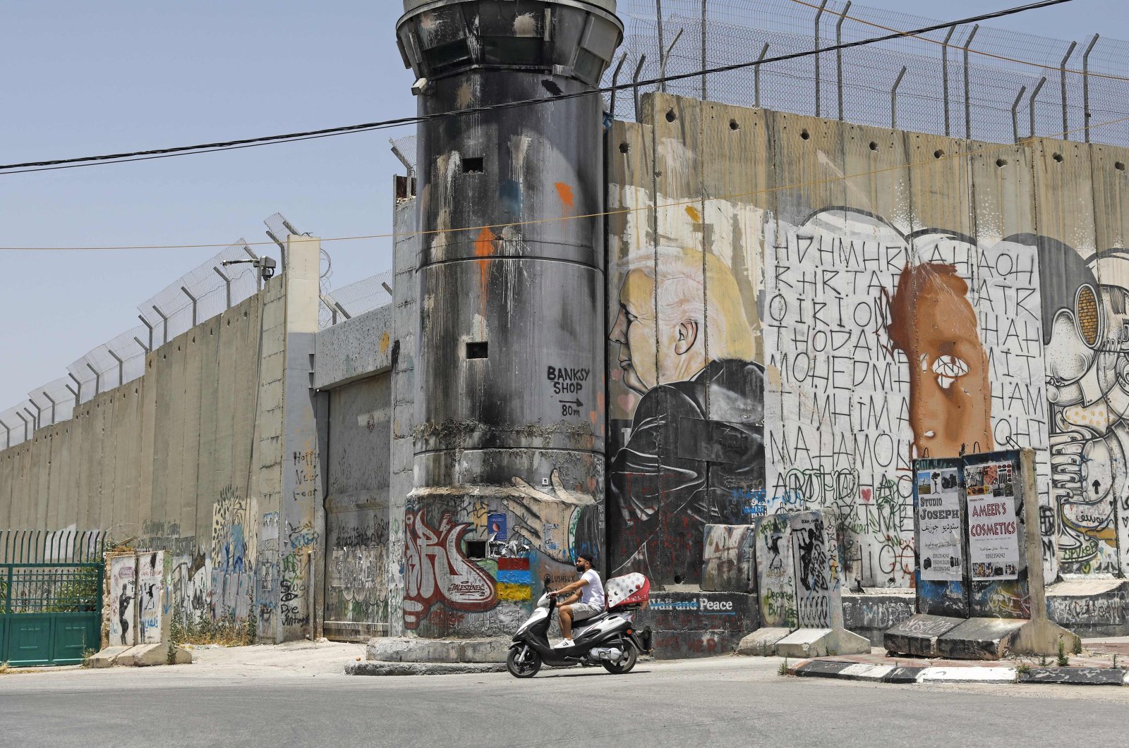 A Palestinian man rides his motorcycle past a mural painting of US President Donald Trump on Israel's controversial separation barrier in the West Bank city of Bethlehem on June 8, 2020. (AFP Photo)