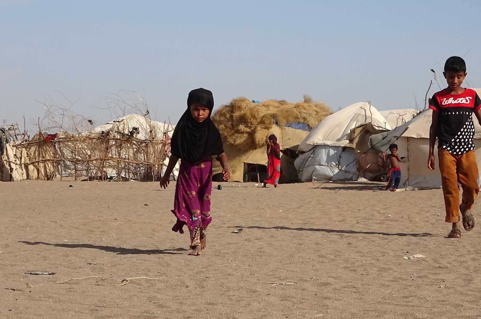 This May 6, 2020, file photo shows children walking past tents at a displaced persons camp in the Khokha district of Hodeida province, western Yemen. (AFP Photo)