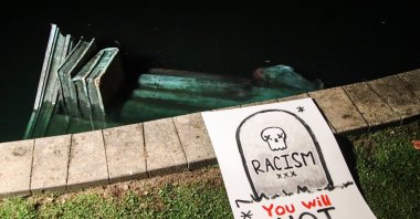 A statue of Christopher Columbus lays in the water at Byrd Park after it was torn down by protesters, Richmond, Virginia, U.S., June 9, 2020 (AP Photo).