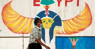 A man wearing a protective face mask walks next to a wall with pharaonic images painted on it, Cairo, June 4, 2020. (REUTERS Photo)