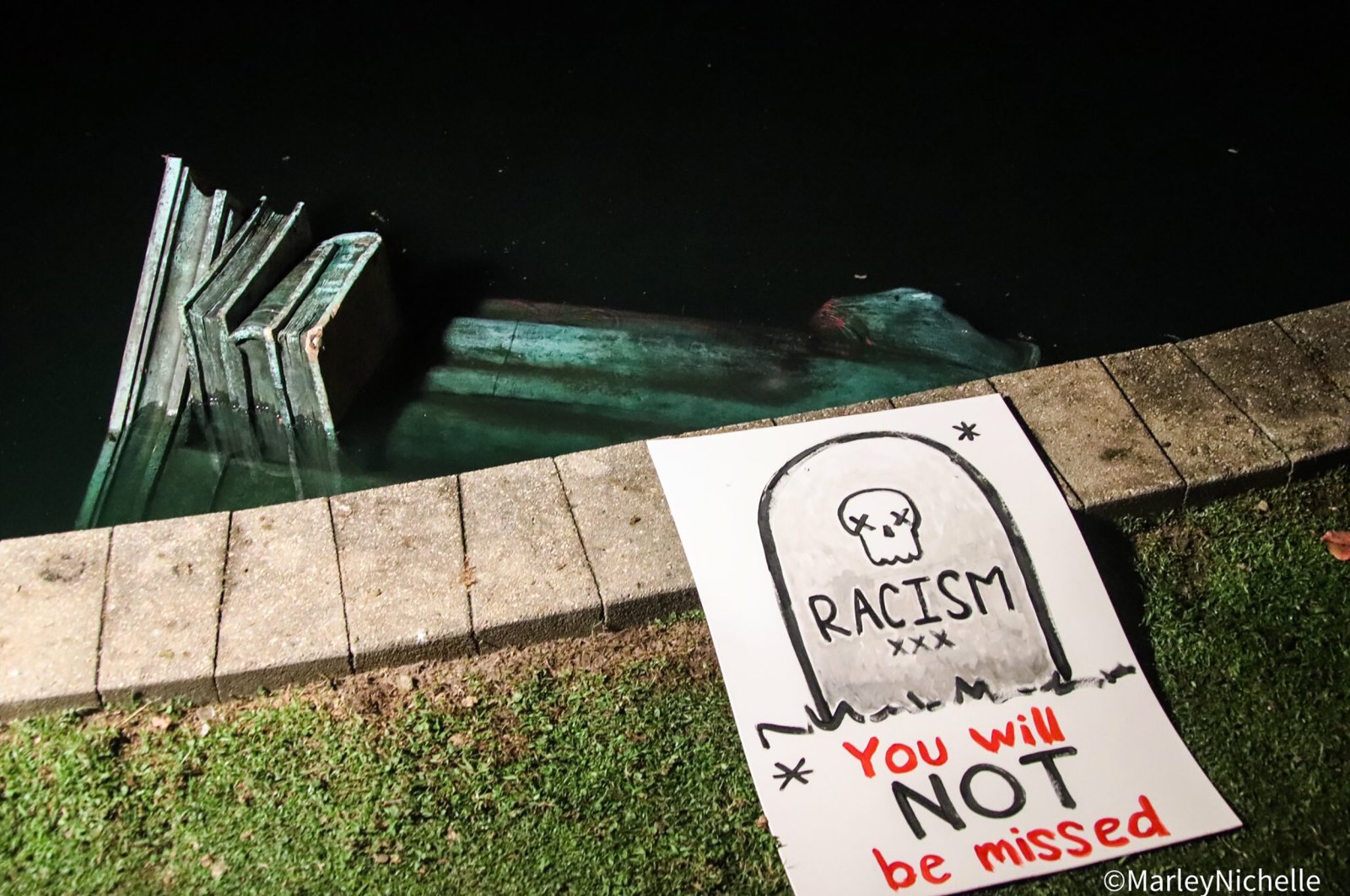 A statue of Christopher Columbus lays in the water at Byrd Park after it was torn down by protesters, Richmond, Virginia, U.S., June 9, 2020 (AP Photo).