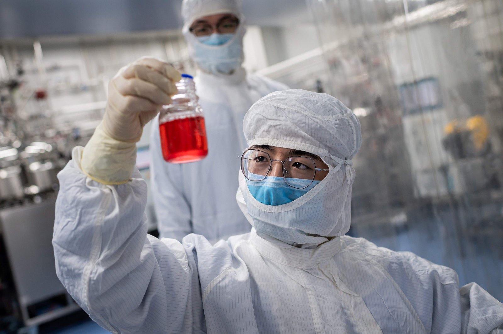 In this April 29, 2020, file photo an engineer looks at monkey kidney cells as he makes a test on an experimental vaccine for the COVID-19 coronavirus inside the Cells Culture Room laboratory at the Sinovac Biotech facilities in Beijing. (Photo by NICOLAS ASFOURI / AFP)