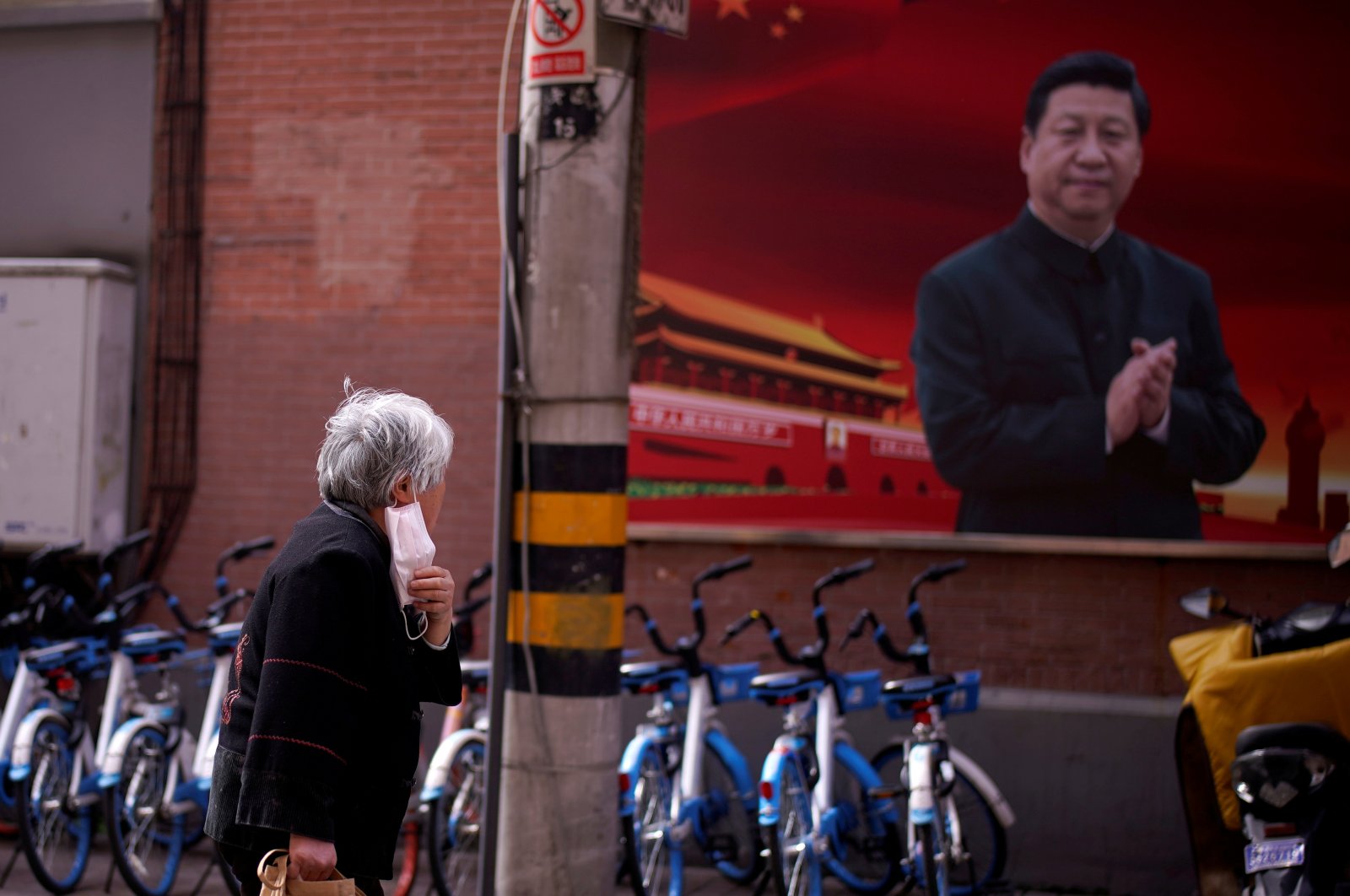 A woman with a protective mask is seen passing a portrait of Chinese President Xi Jinping on a street as the country is hit by an outbreak of the coronavirus, in Shanghai, China, March 12, 2020. (Reuters Photo)