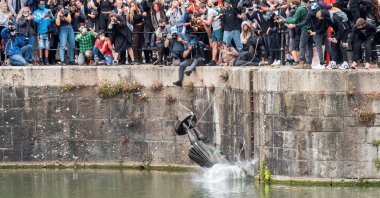 The statue of 17th-century slave trader Edward Colston falls into the water after protesters pulled it down and pushed off a dock, Bristol, June 7, 2020. (REUTERS Photo)