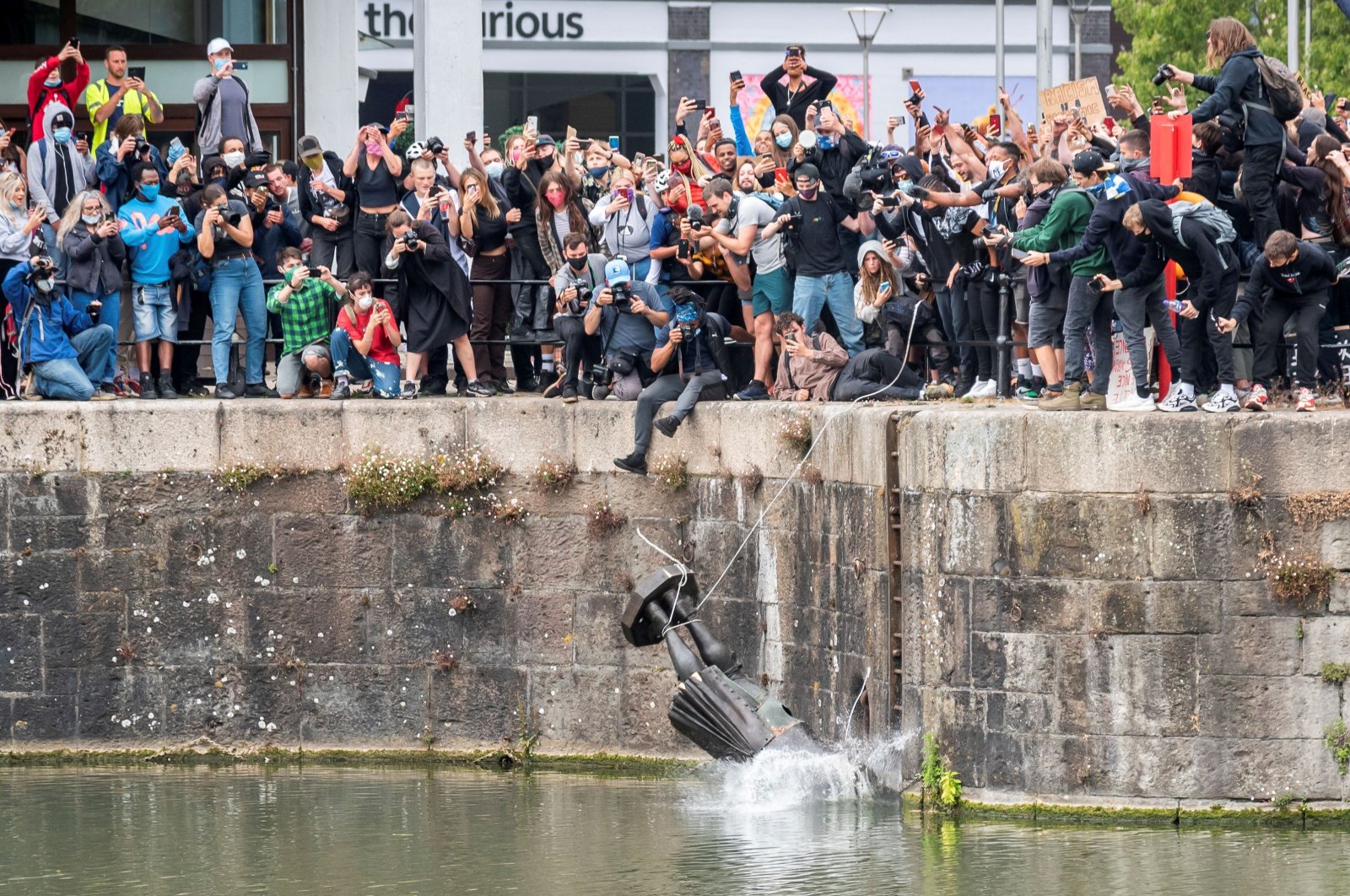 The statue of 17th-century slave trader Edward Colston falls into the water after protesters pulled it down and pushed off a dock, Bristol, June 7, 2020. (REUTERS Photo)