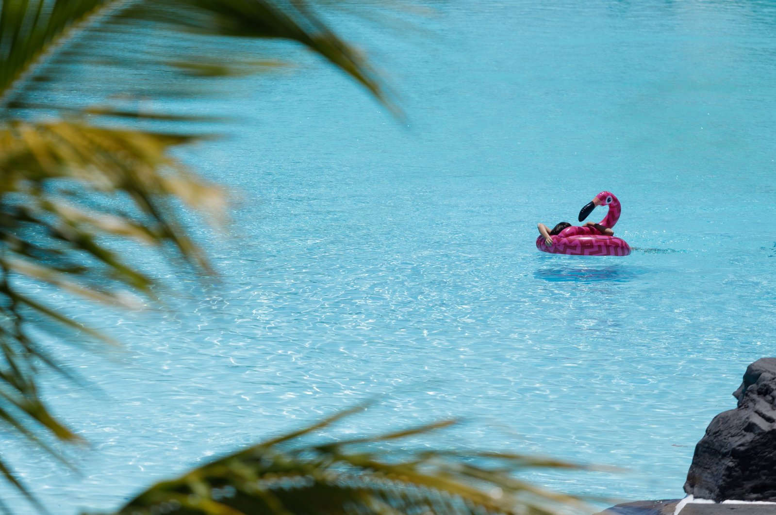 A girl enjoys a warm day atop a pink flamingo pool float in a hotel swimming pool, in Santa Cruz de Tenerife, Canary Islands, Spain, May 26, 2020. (EPA Photo)