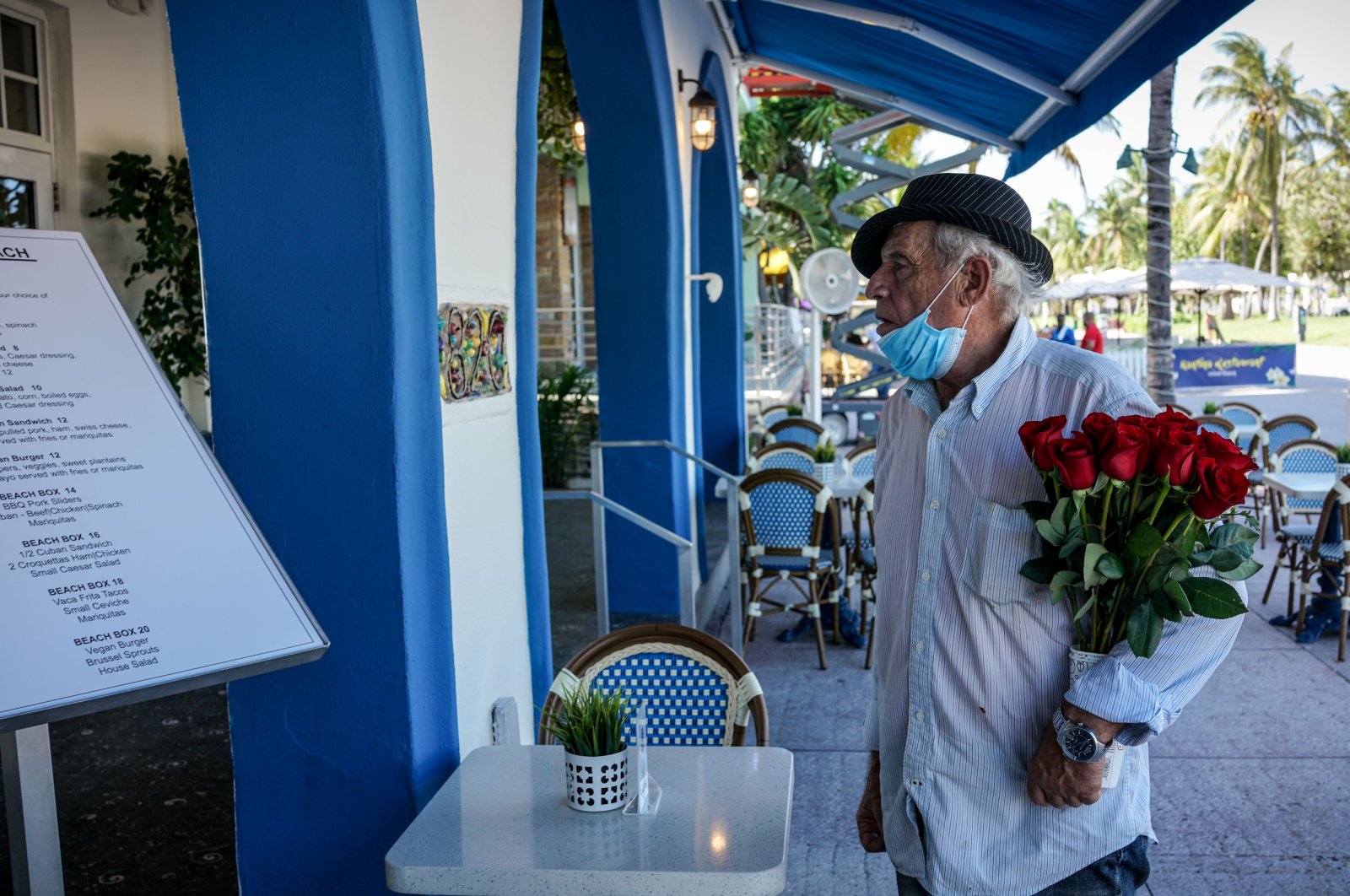 In this file photo taken on June 9, 2020, an elderly man holds a bouquet of roses as he looks at the menu outside a restaurant on Ocean Drive in South Beach, Miami. (AFP Photo)