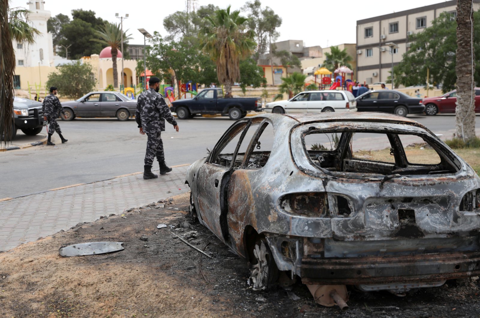 Libyan policemen walk near a damaged car during a security deployment in Tarhouna city, June 11, 2020. (REUTERS)
