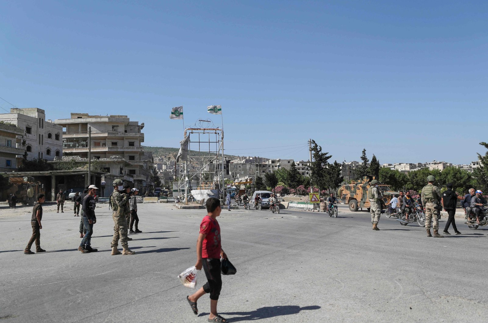 Syrians pass by Turkish soldiers during a joint Russian-Turkish patrol along the M4 highway, which links the northern Syrian provinces of Aleppo and Latakia, near Ariha in Syria's opposition-held northwestern Idlib province, June 10, 2020. (AFP Photo)