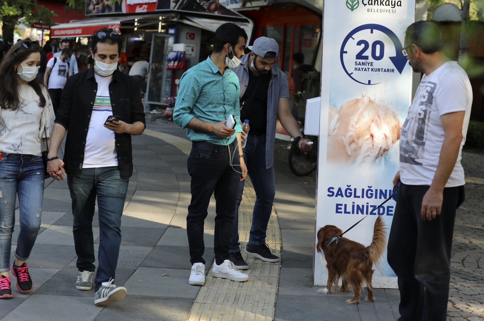 People wearing face masks use disinfectant at the entrance of a public garden, in Ankara, Turkey, June 14, 2020. (AP Photo)