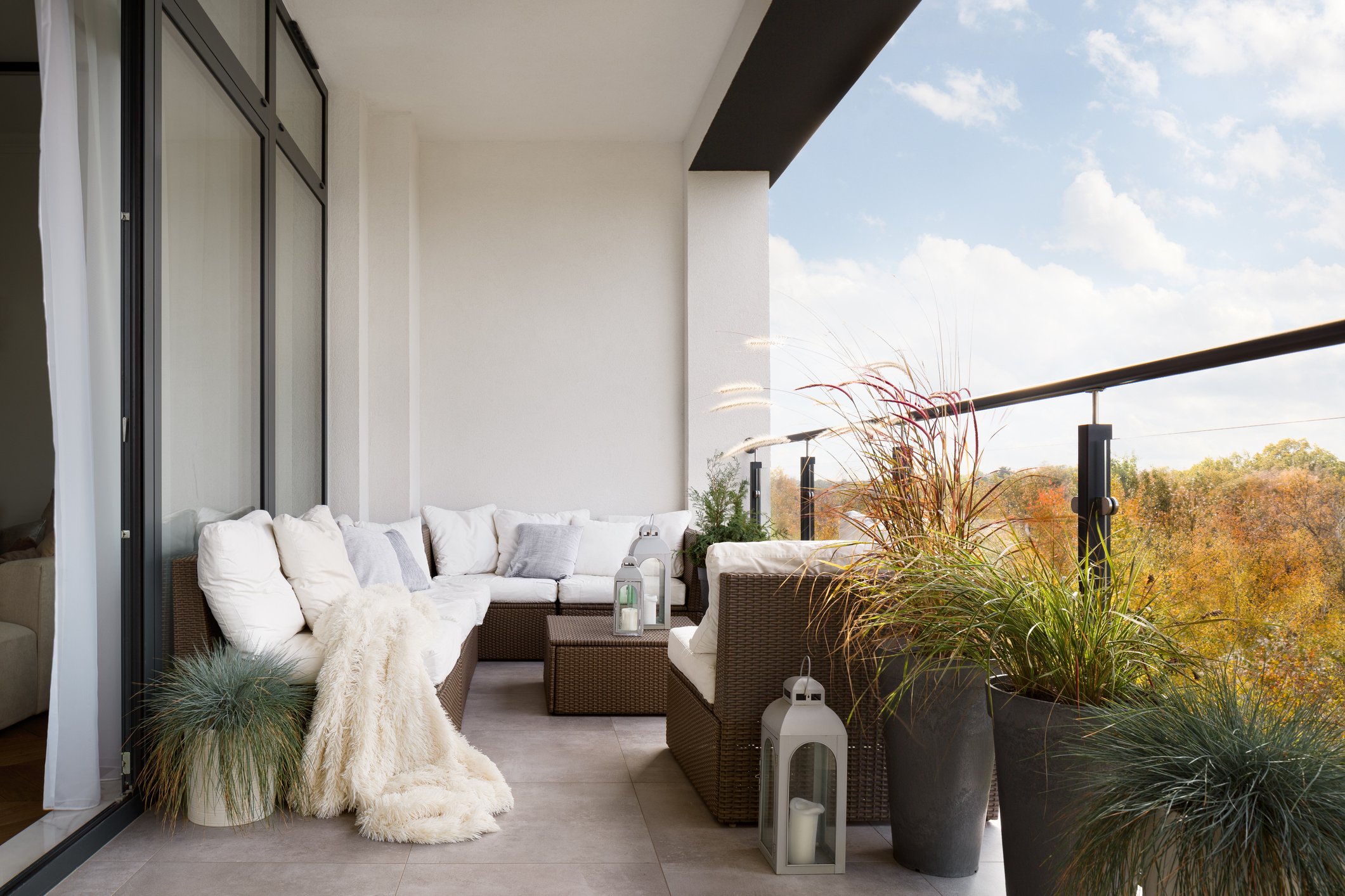 Rattan furniture, bright pillows and plants add an elegant touch to an otherwise boring balcony. (iStock Photo)