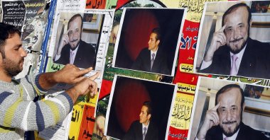 A man pastes pictures of Rifaat Assad (R), the younger brother of late Syrian President Hafez Assad and uncle of Bashar Assad, and Rifaat Assad's son Ribal on a wall in the northern city of Tripoli, Lebanon, Dec. 6, 2007. (AFP Photo)