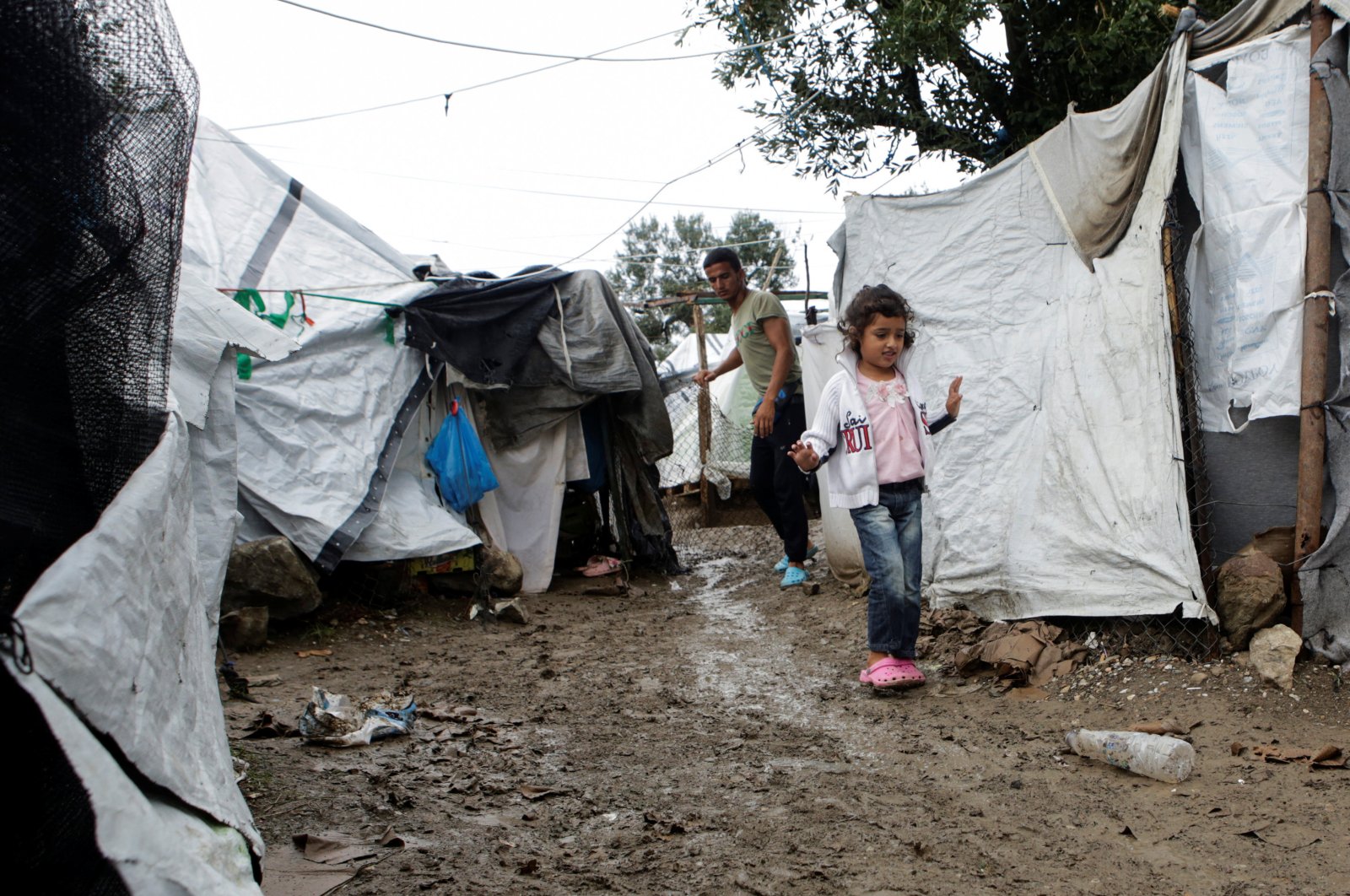 A girl walks next to tents at a makeshift camp for refugees and migrants next to the Moria camp, following rainfall on the island of Lesbos, Greece, Oct. 8, 2019. (Reuters Photo)