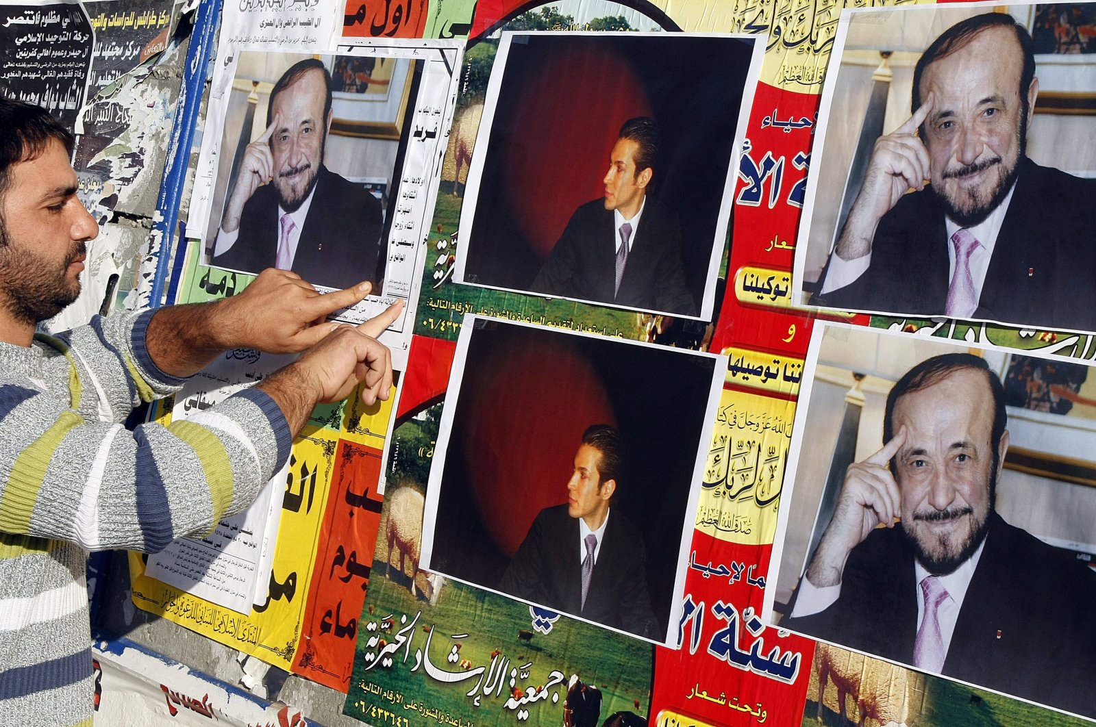 A man pastes pictures of Rifaat Assad (R), the younger brother of late Syrian President Hafez Assad and uncle of Bashar Assad, and Rifaat Assad's son Ribal on a wall in the northern city of Tripoli, Lebanon, Dec. 6, 2007. (AFP Photo)