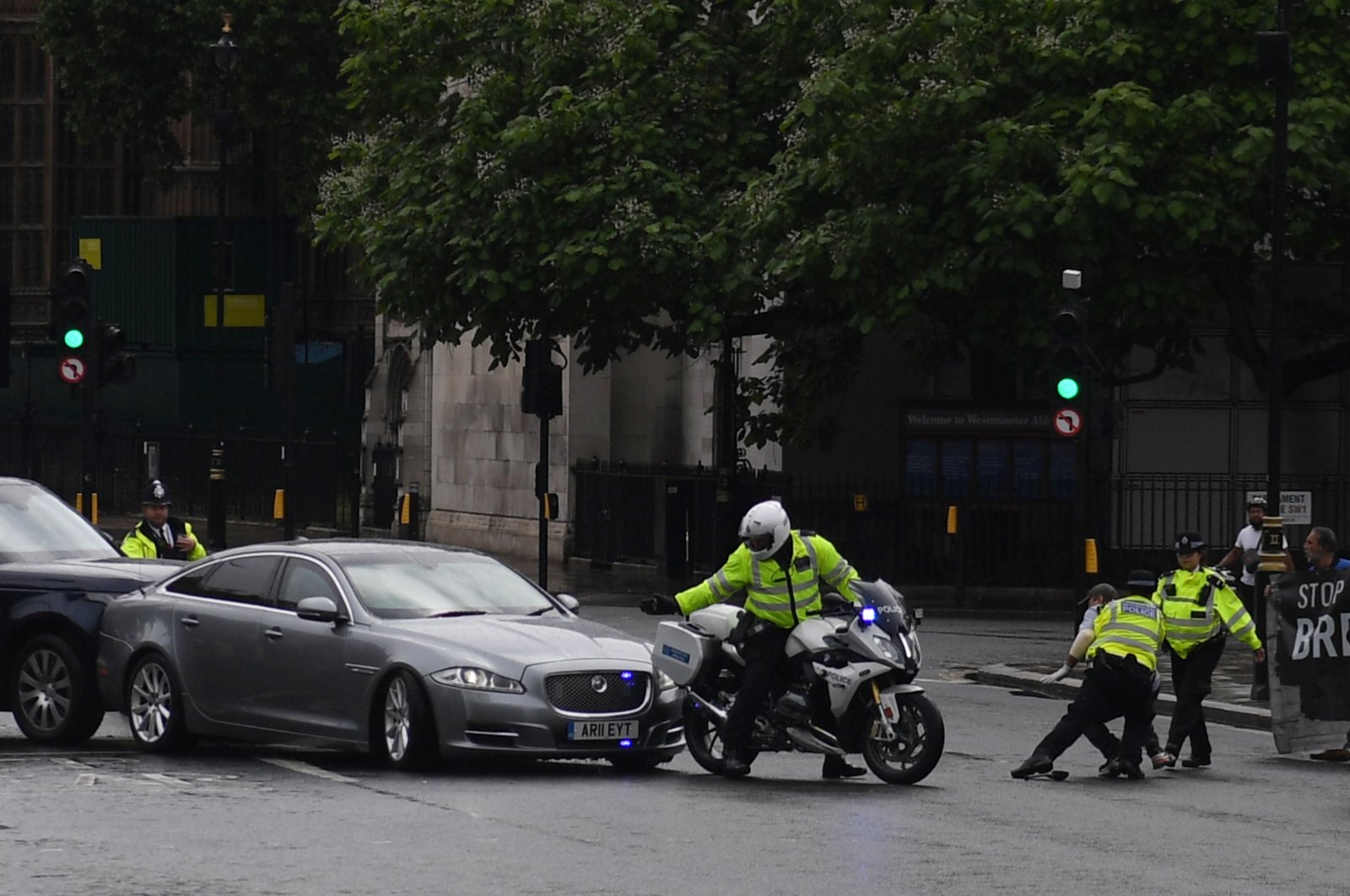 A protester from a demonstration is stopped and detained by police officers as he ran towards the car of Britain's Prime Minister Boris Johnson (C) as it was leaving with a police escort from the Houses of Parliament, London, June 17, 2020. (AFP Photo)