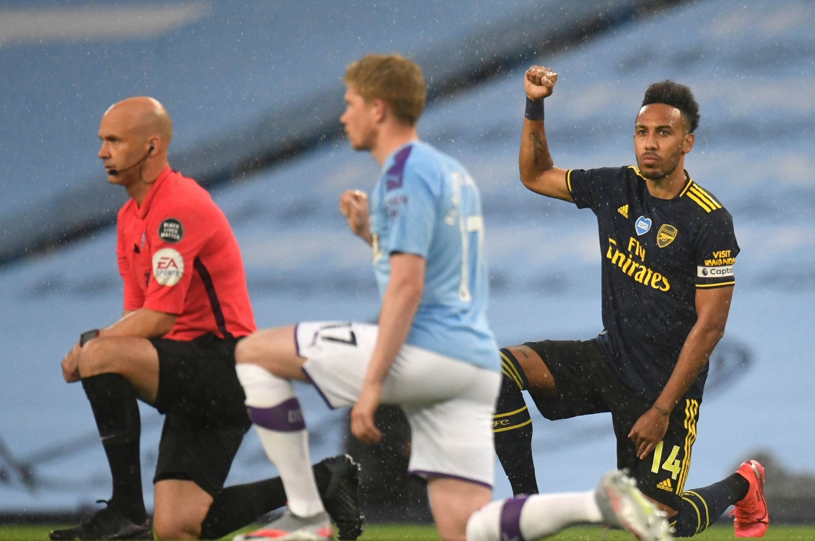 Arsenal's Gabonese striker Pierre-Emerick Aubameyang (R) takes a knee alongside Manchester City's Belgian midfielder Kevin De Bruyne (C) and Referee Anthony Taylor (L) ahead of the English Premier League football match between Manchester City and Arsenal at the Etihad Stadium in Manchester, northwest England, June 17, 2020. (AFP Photo)