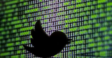 A 3D printed Twitter logo seen in front of a displayed cyber code. (Reuters Photo)