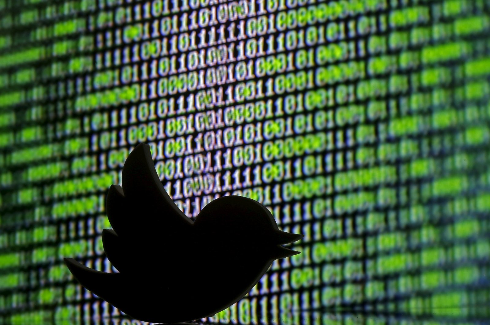 A 3D printed Twitter logo seen in front of a displayed cyber code. (Reuters Photo)