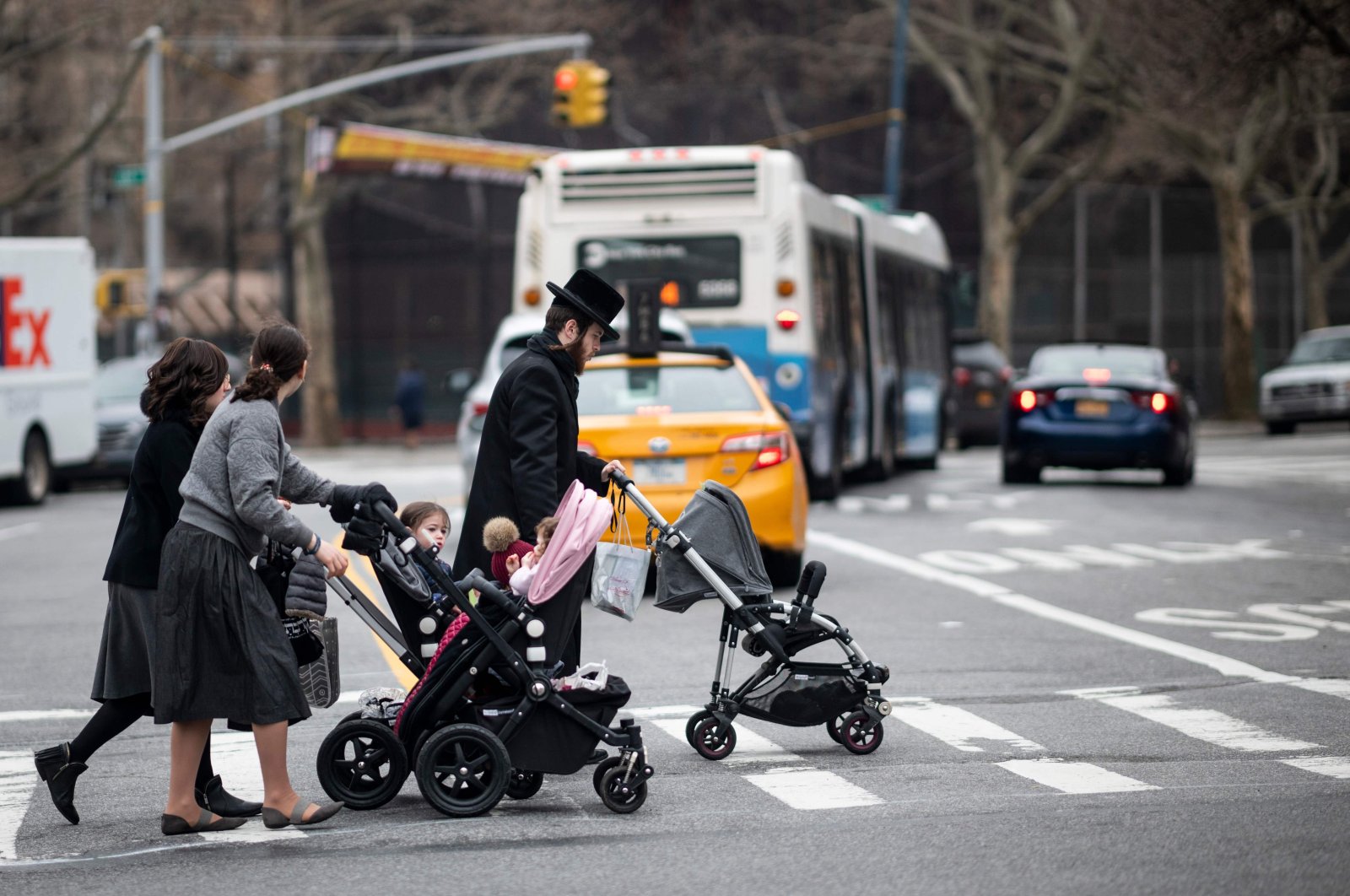 A Jewish man and two woman pushes strollers as they cross a street in a Jewish quarter in Williamsburg Brooklyn, New York City, April 9, 2019. (AFP Photo)