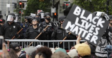 Police officers behind a barricade look on as protesters fill the street in front of Seattle City Hall, following protests over the death of George Floyd, a black man who was killed in police custody in Minneapolis, Seattle, Washington, U.S., June 3, 2020. (AP Photo)
