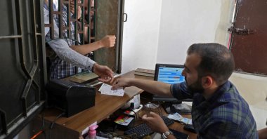 A Syrian man receives Turkish liras at a currency exchange shop in the town of Sarmada in Syria's northwestern Idlib province, June 15, 2020. (AFP Photo)