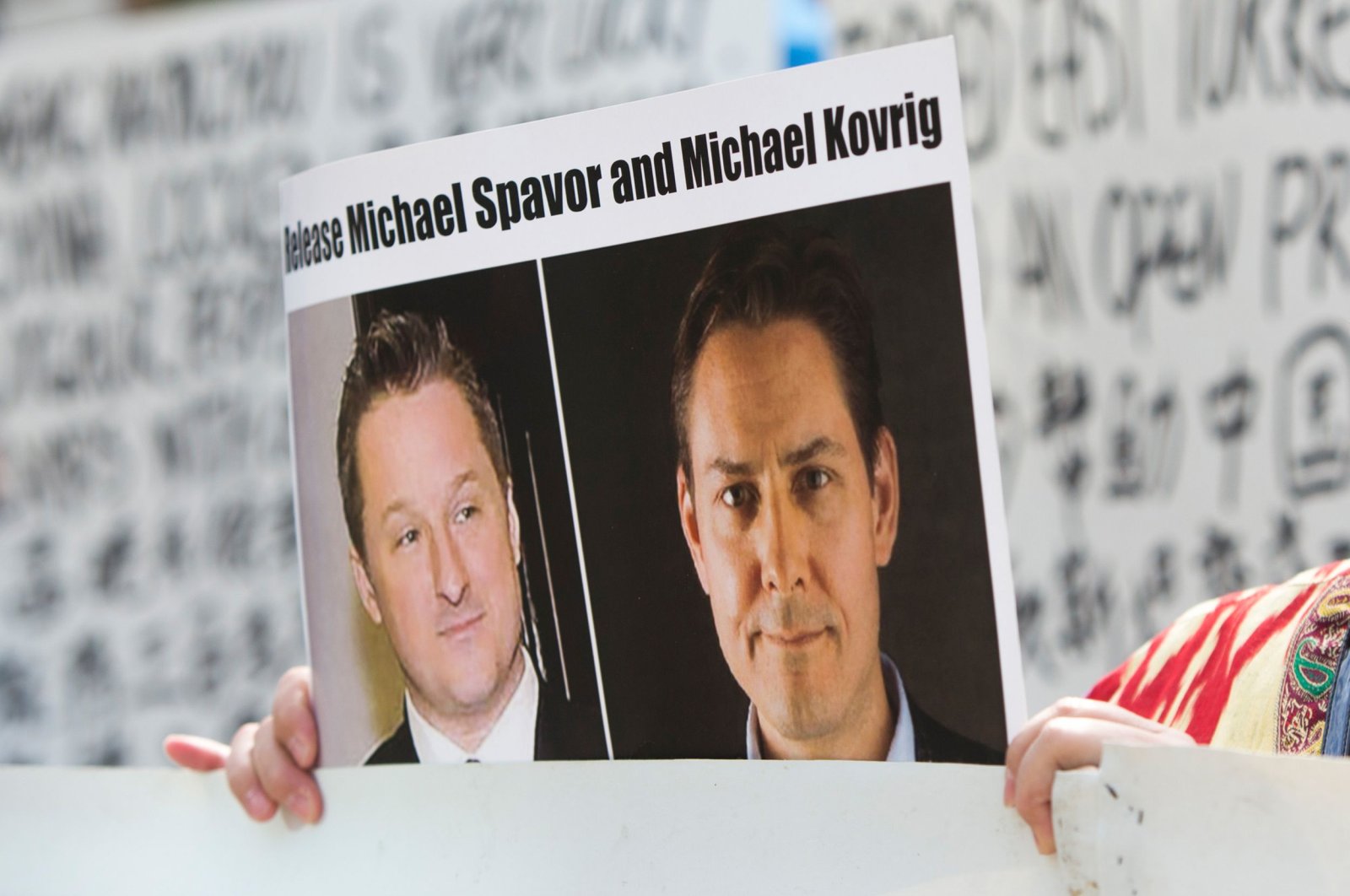 In this May 8, 2019, file photo, a protester holds up a placard depicting detained Canadians Michael Spavor, left, and Michael Kovrig outside a court during a hearing for Huawei Chief Financial Officer, Meng Wanzhou at the British Columbia Supreme Court in Vancouver, Canada. (AFP Photo)