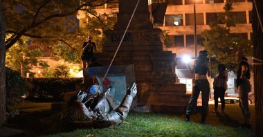 People stand around the statue of Confederate general Albert Pike after it was toppled by protesters at Judiciary Square in Washington, DC on late June 19, 2020. (AFP Photo)