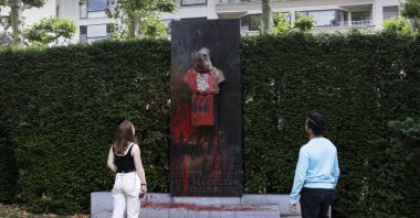 A couple stop to look at a bust of Belgium's King Leopold II, which has been damaged by red paint, graffiti and cement, at a park in Ghent, Belgium on Friday, June 19, 2020. Protests sweeping the world after George Floyd's death in the U.S. have added fuel to a movement to confront Europe's role in the slave trade and its colonial past.(AP Photo)