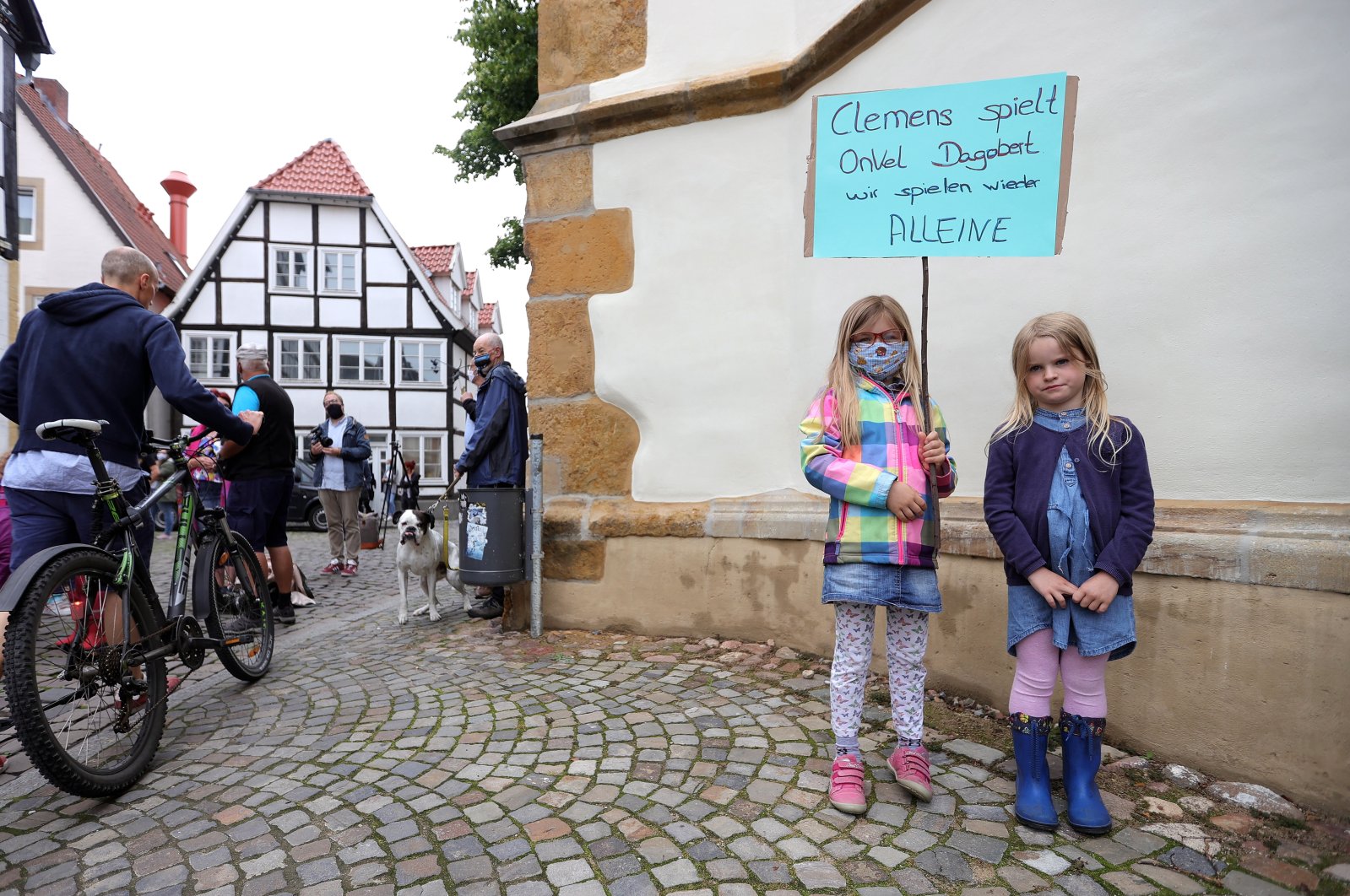 Two children pose with a sign reading 'Clemens plays Uncle Scrooge, we play alone again' as they protest against the closure of schools and kindergartens in Rheda-Wiedenbrueck, western Germany, 18 June 2020. (EPA Photo)