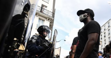 A protester wearing a face mask stands in front of police during a demonstration against racism and police brutality and in memory of Lamine Dieng, a French-Senegalese 25 year-old who died after his arrest in 2007, in Paris, June 20, 2020. (AFP File Photo)
