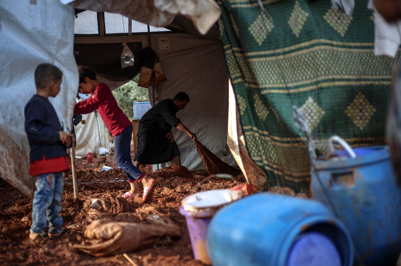 A displaced Syrian family is seen clearing mud from their tent after heavy rains caused devastating damage in camps in northwestern Syria, June 19, 2020. (AA Photo)