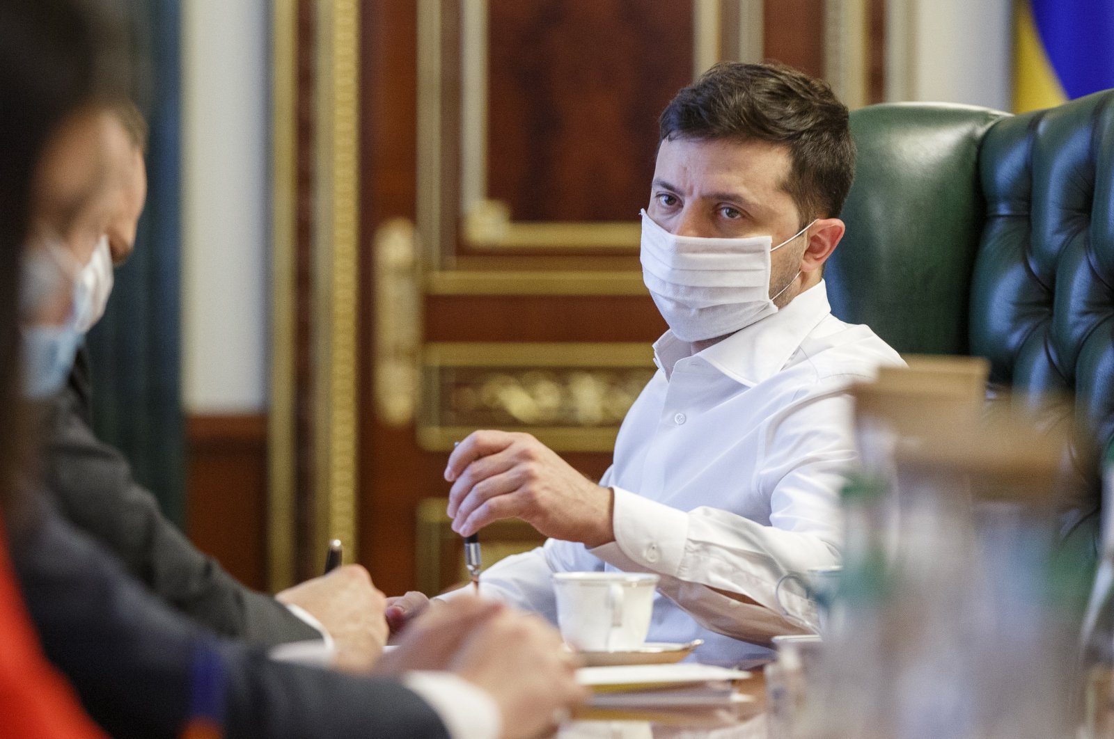 Ukrainian President Volodymyr Zelenskiy in a face mask to protect against coronavirus, discusses the COVID-19 situation in the country with officials in his office in Kyiv, Ukraine on April 22, 2020. (AP Photo)