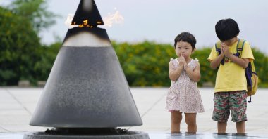 Children pray in front of the "Peace of Fire" at the Peace Memorial Park in Itoman, Okinawa, Japan, June 23, 2020. (AP Photo)