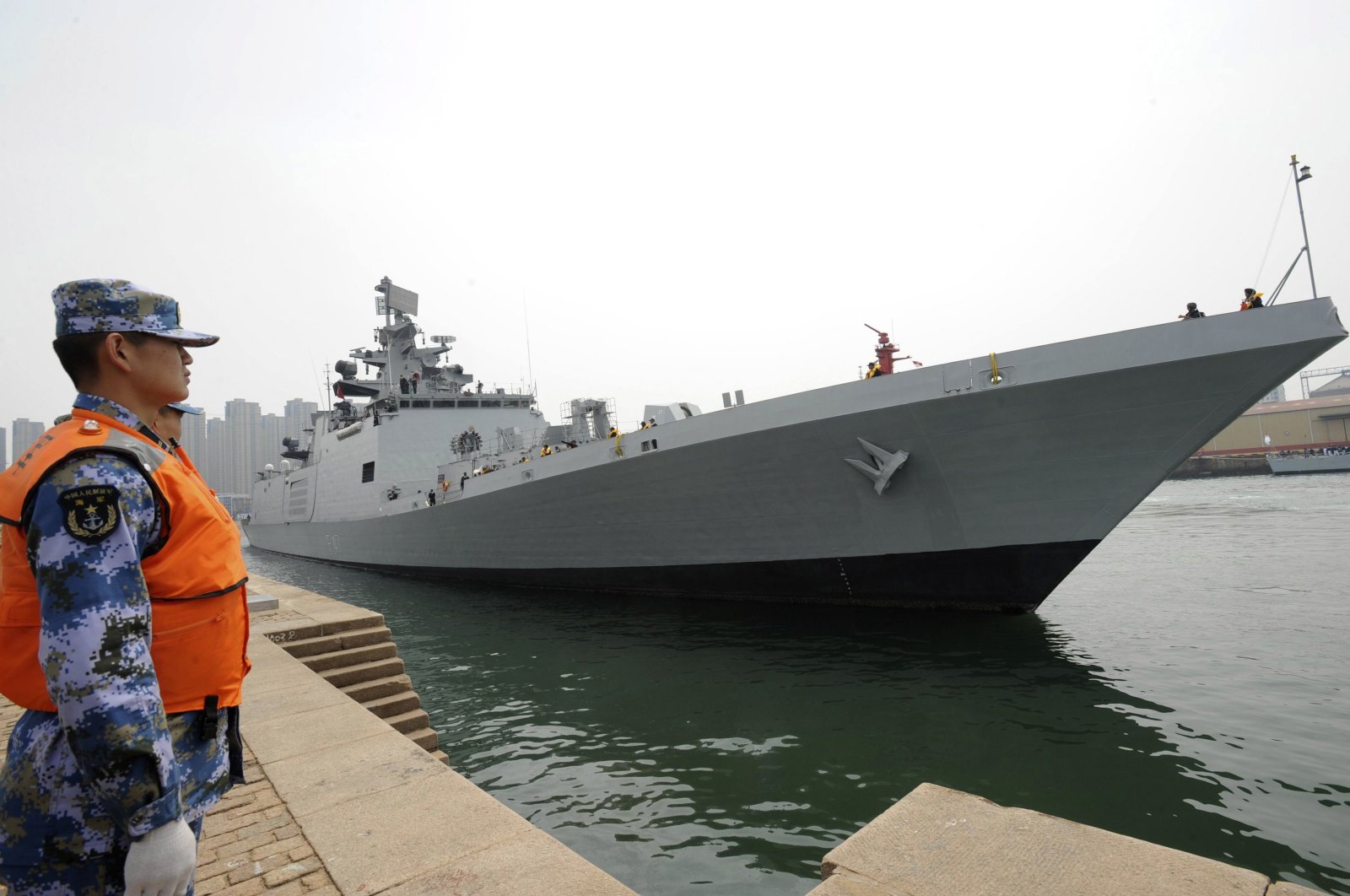 A Chinese navy personnel (L) stands guard as Indian naval frigate INS SHIVALIK is seen docked at a military port after its arrival before a maritime drill during the Western Pacific Naval Symposium in Qingdao, Shandong province, April 20, 2014. (Reuters Photo)
