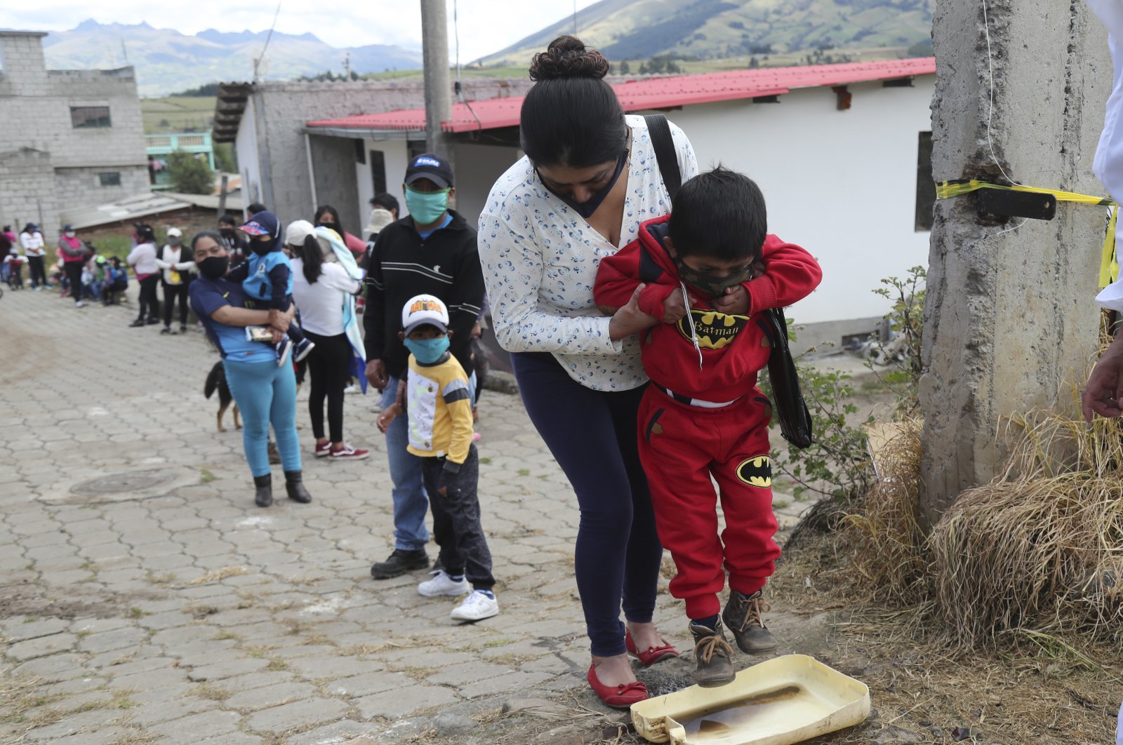 A woman helps her son to disinfect his shoes before entering the Cariacu stadium, Ecuador, June 17, 2020. (AP Photo)