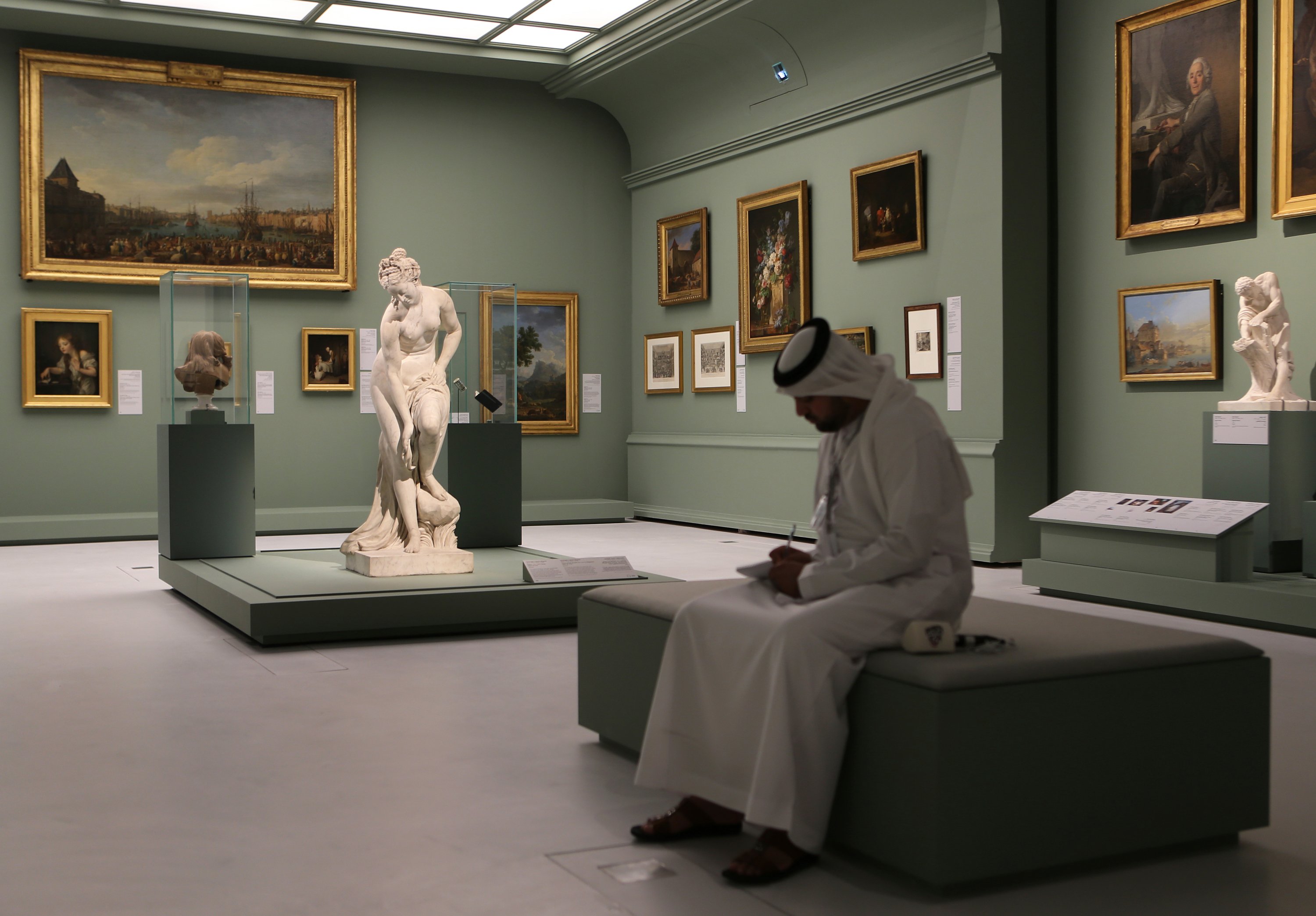 An Emirati journalist writes next to the Bather, also called Venus statue by Christophe-Gabriel Allegrain, 1710-1795, at the Louvre Museum in Abu Dhabi, United Arab Emirates, Dec. 19, 2017. (AP PHOTO)