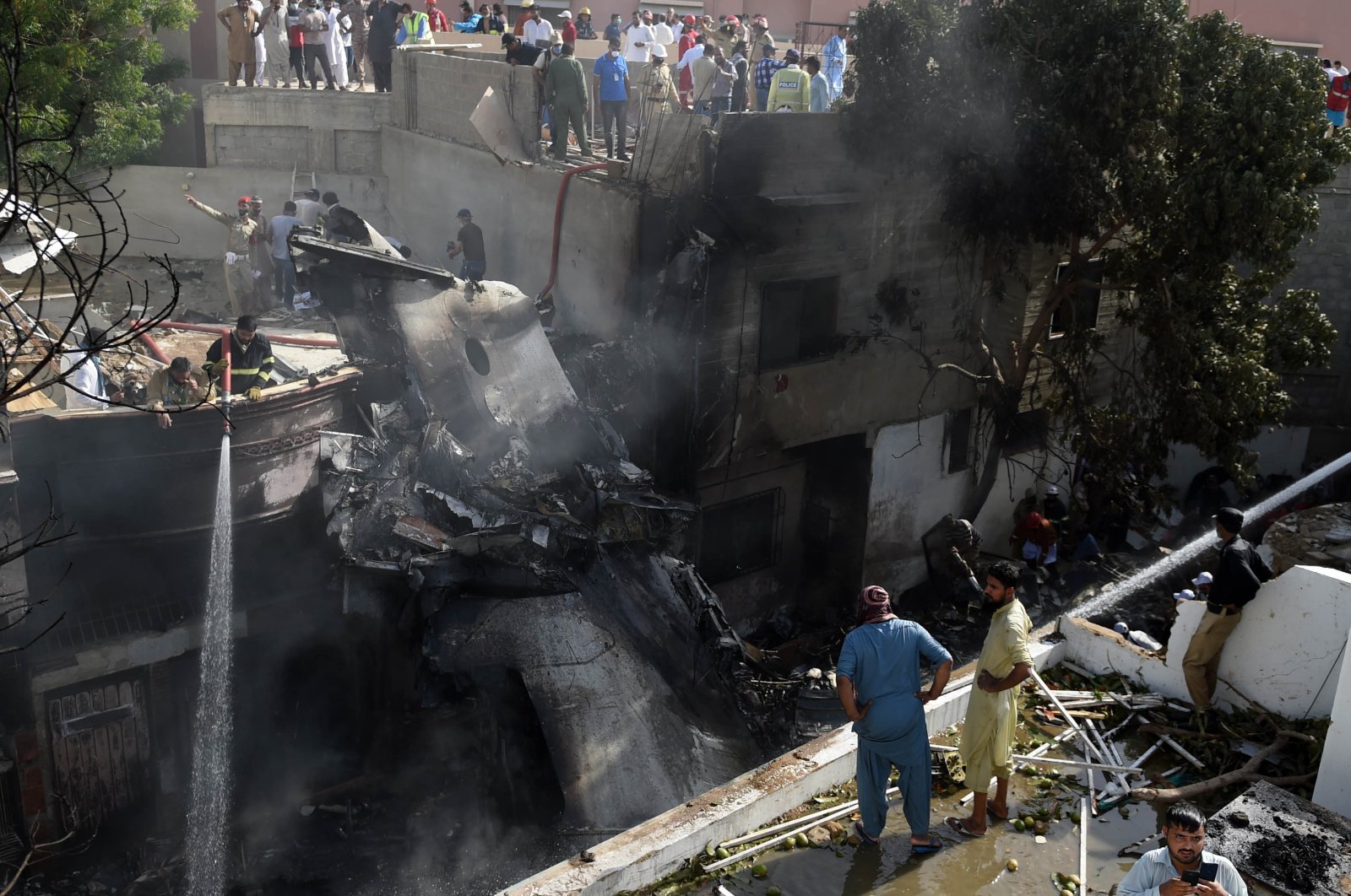 Locals inspect the wreckage of a passenger plane of state-run Pakistan International Airlines, at the scene after it crashed in a residential area, in Karachi, Pakistan, May 22, 2020. (EPA-EFE Photo)