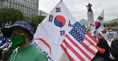 A South Korean woman holds flags of South Korea and the U.S. during a rally commemorating the 70th anniversary of the beginning of the Korean War in Seoul on June 25, 2020. (AFP Photo)