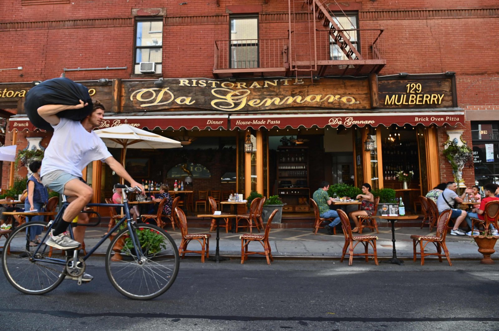 A biker goes past a restaurant with outdoor seating in the Little Italy neighborhood, New York City, June 24, 2020. (AFP Photo)