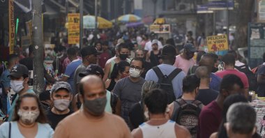 Pedestrians, some wearing protective face masks, walk through a street market in downtown, Rio de Janeiro, Brazil, June 25, 2020. (AP Photo)