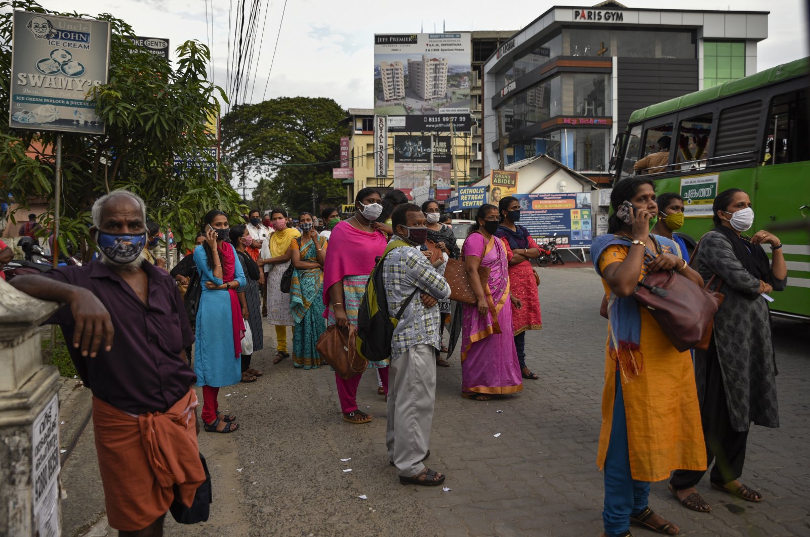 People wearing masks as a precaution against the coronavirus wait for transportation in Kochi, Kerala state, India, Thursday, June 25, 2020. (AP Photo)