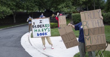 Protesters hold signs as President Donald Trump arrives at Trump National Golf Club, Sunday, June 28, 2020, in Sterling, Va. (AP Photo)