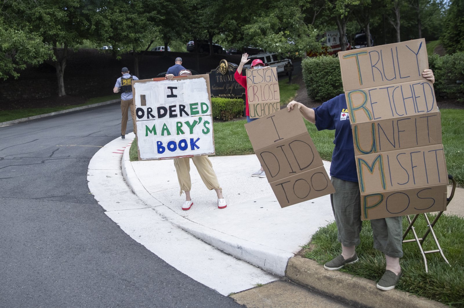 Protesters hold signs as President Donald Trump arrives at Trump National Golf Club, Sunday, June 28, 2020, in Sterling, Va. (AP Photo)