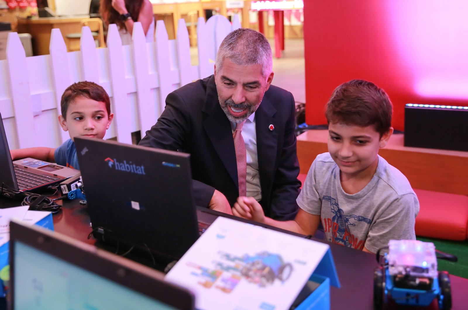 The chairman of Turkey Vodafone Foundation Hasan Süel sits between two children receiving coding courses. (Takvim File Photo)