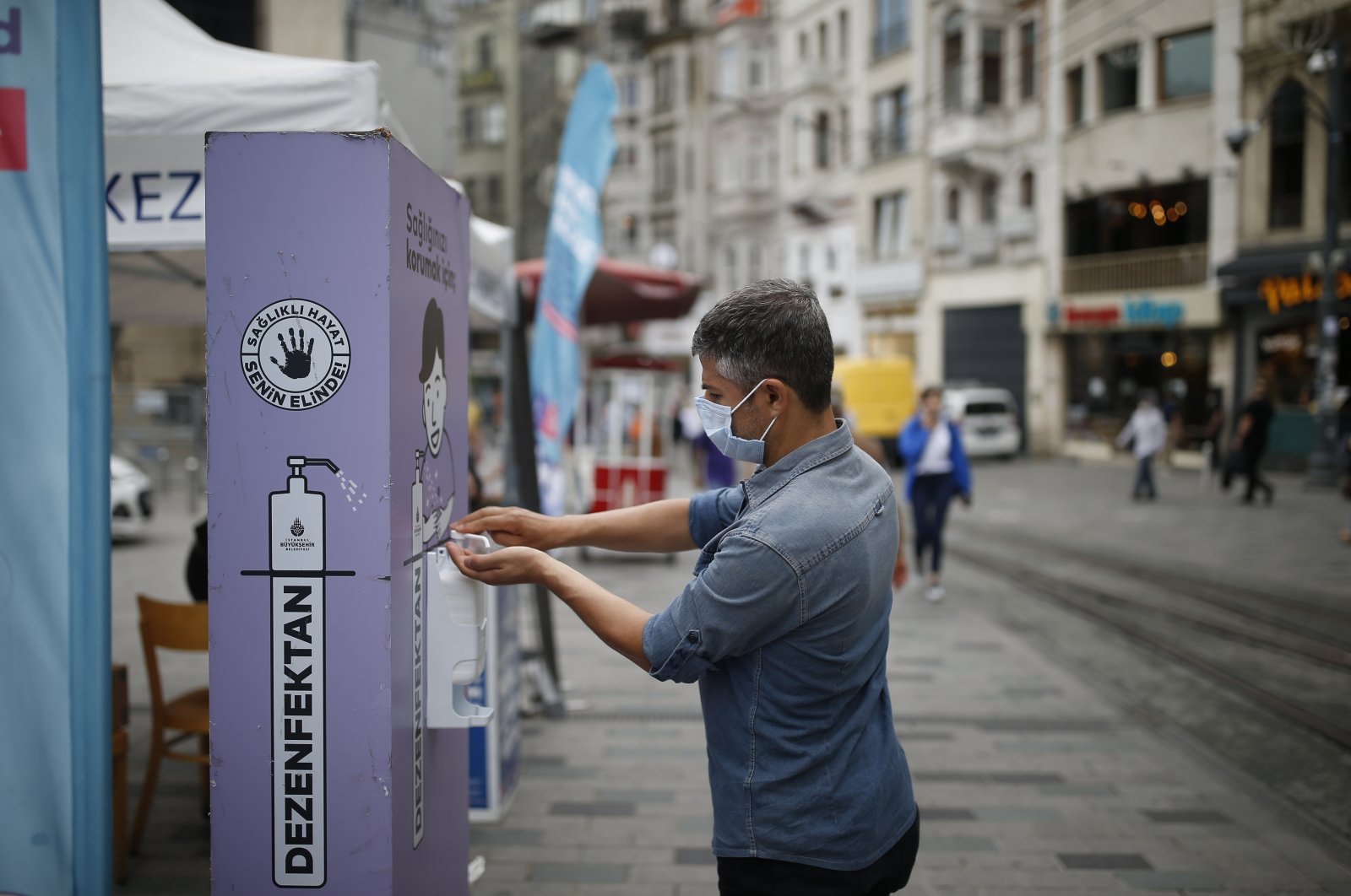 A man, wearing a protective mask against the spread of coronavirus, uses disinfectant from a public station on Istiklal street, the main shopping street in Istanbul, Thursday, June 18, 2020. (AP Photo)