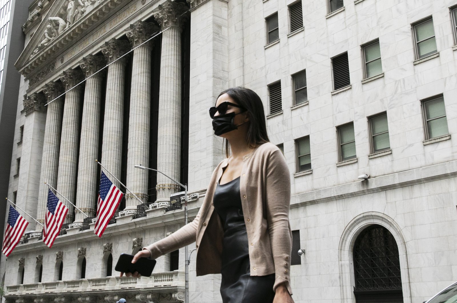 A woman wearing a mask passes the New York Stock Exchange, Tuesday, June 30, 2020, during the coronavirus pandemic. (AP Photo)