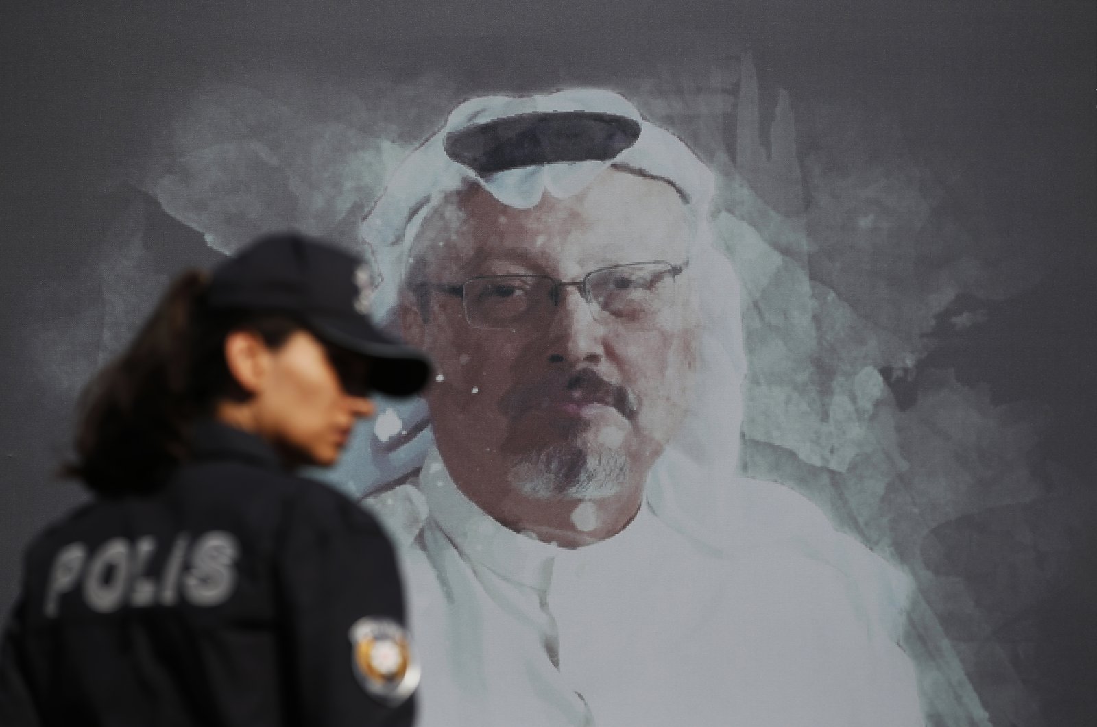 A Turkish police officer walks past a picture of slain Saudi journalist Jamal Khashoggi prior to a ceremony, near the Saudi Arabia consulate in Istanbul, marking the one-year anniversary of his death, Wednesday, Oct. 2, 2019. (AP Photo)