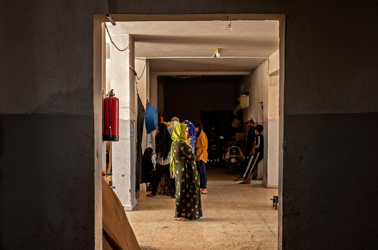 People stand in a hallway at a school building where Syrians, displaced from the area of Ras al-Ain, are staying in the city of Hasakah, Syria, June 30, 2020. (AFP Photo)