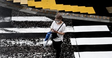 A woman uses her phone while crossing a street in Yamato, Kanagawa prefecture, July 1, 2020. (AFP Photo)